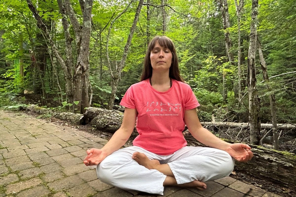 Woman meditating in the forest during Sadhana Intensive